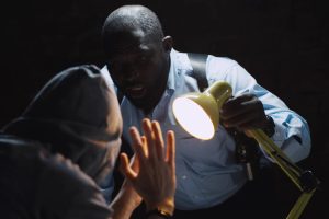 African,Officer,Interrogating,Man,Suspected,Of,Crime,Glowing,Light,Of