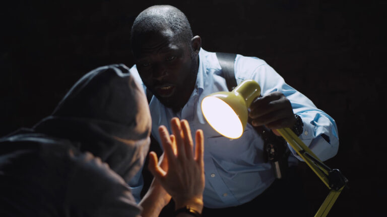 African,Officer,Interrogating,Man,Suspected,Of,Crime,Glowing,Light,Of