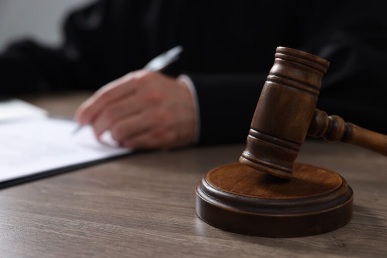 Judge,With,Gavel,Writing,In,Papers,At,Wooden,Table,,Closeup
