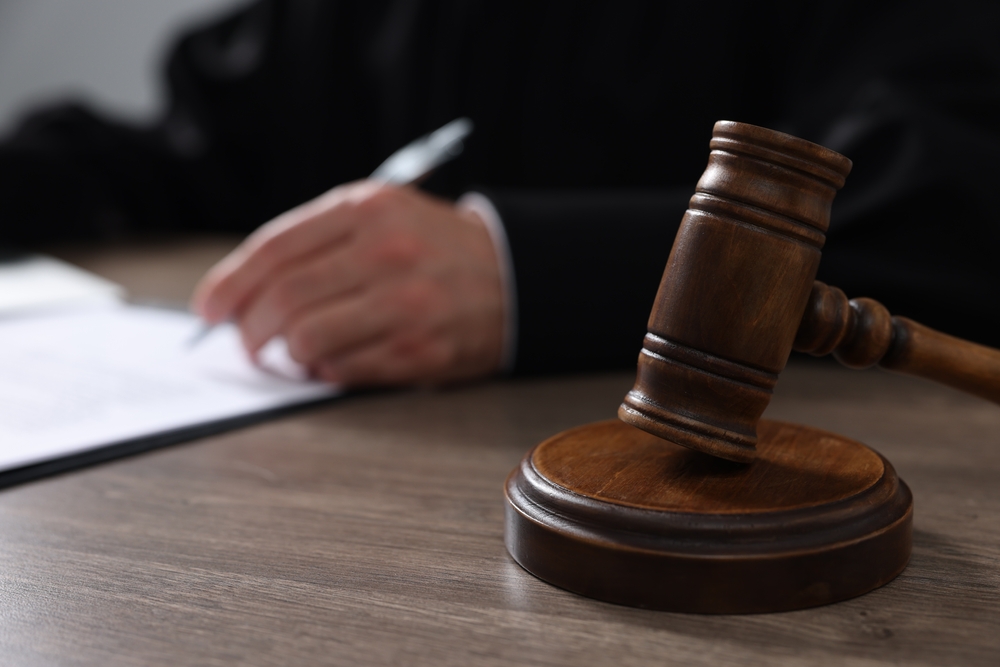Judge,With,Gavel,Writing,In,Papers,At,Wooden,Table,,Closeup