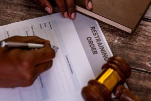 Hands,Filling,Out,A,Restraining,Order,Form,With,A,Gavel