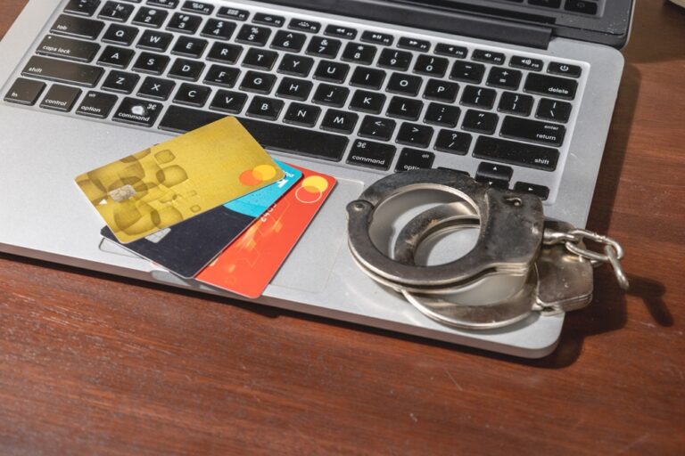 Handcuffs,Rest,Beside,A,Laptop,And,Credit,Cards,,Visually,Portraying